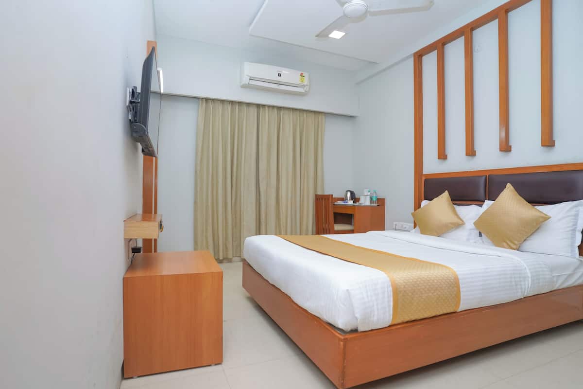 A hotel room with a wooden bed, a bedside table, a desk, an air conditioning unit, and a ceiling fan.
