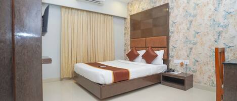 A hotel room with a large bed, a nightstand, a ceiling fan, an air conditioning unit, and a decorative wall panel.