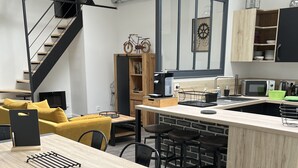 Ett modernt kök med en central köksö, barstolar, en kaffemaskin och en mikrovågsugn.