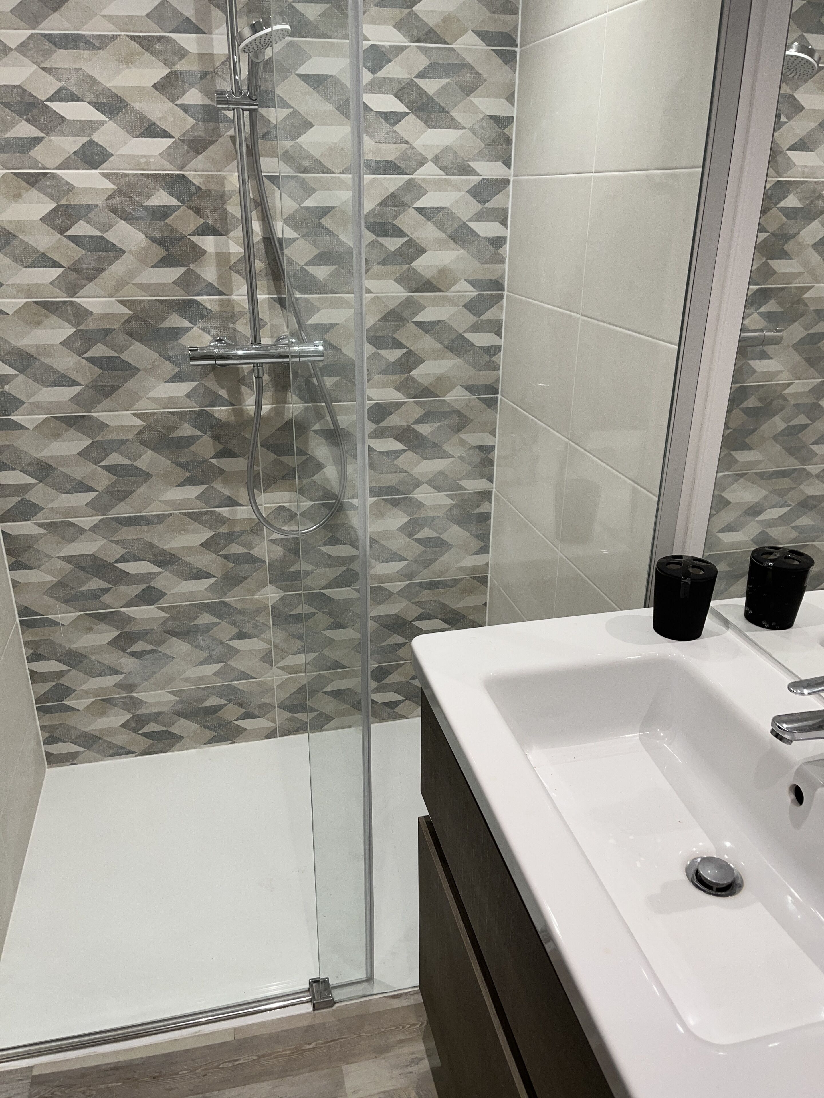 A bathroom with a shower, a sink, and a mirror.