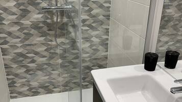 A bathroom with a shower, a sink, and a mirror.