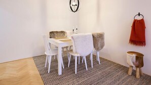 A modern dining area with a white table and chairs, a patterned rug, and a hanging orange scarf. - Harrachov 377 by Interhome (Harrachov)