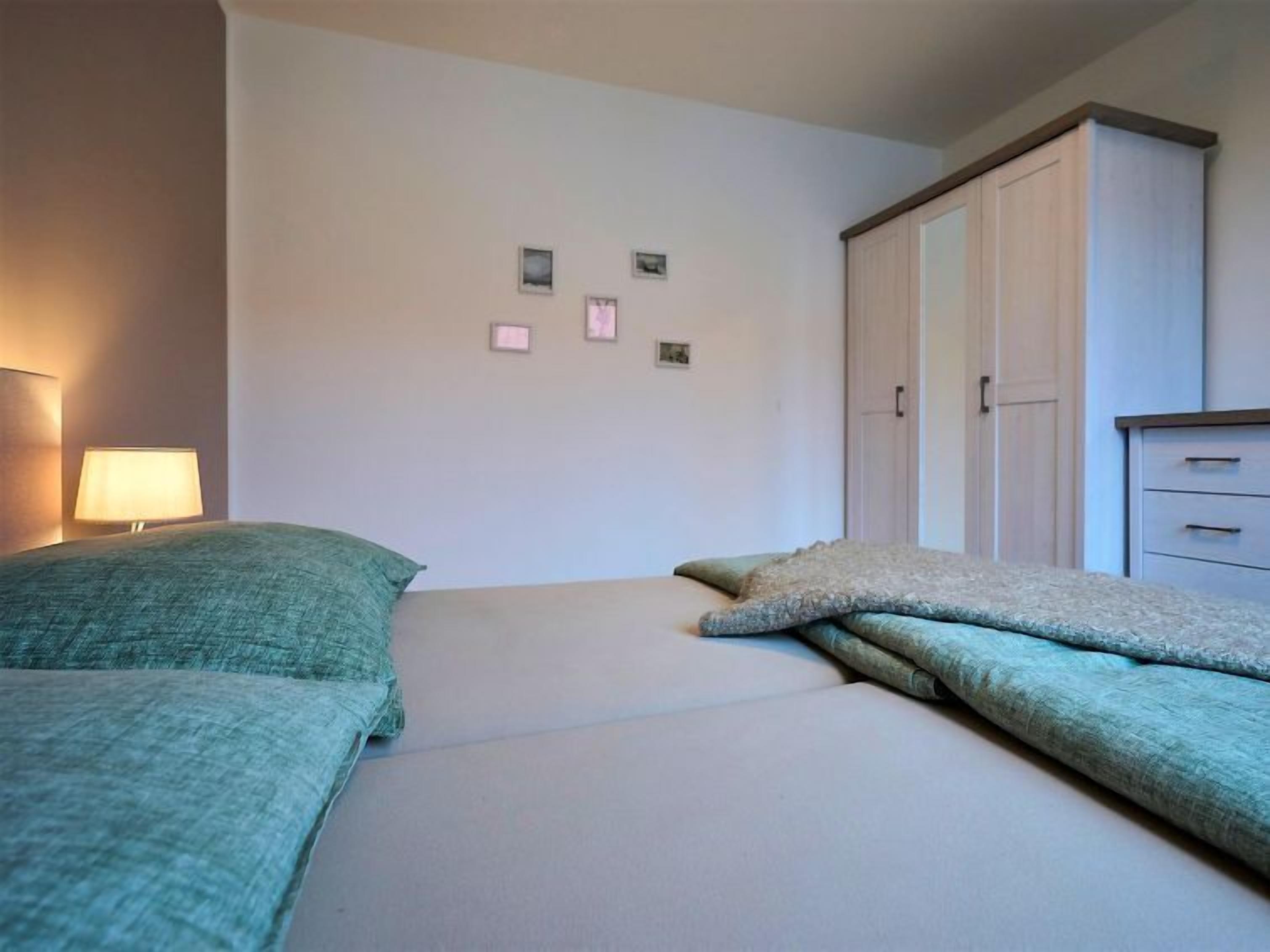 Une chambre à coucher comprenant un lit, une table de chevet, une lampe, une armoire et une commode.
