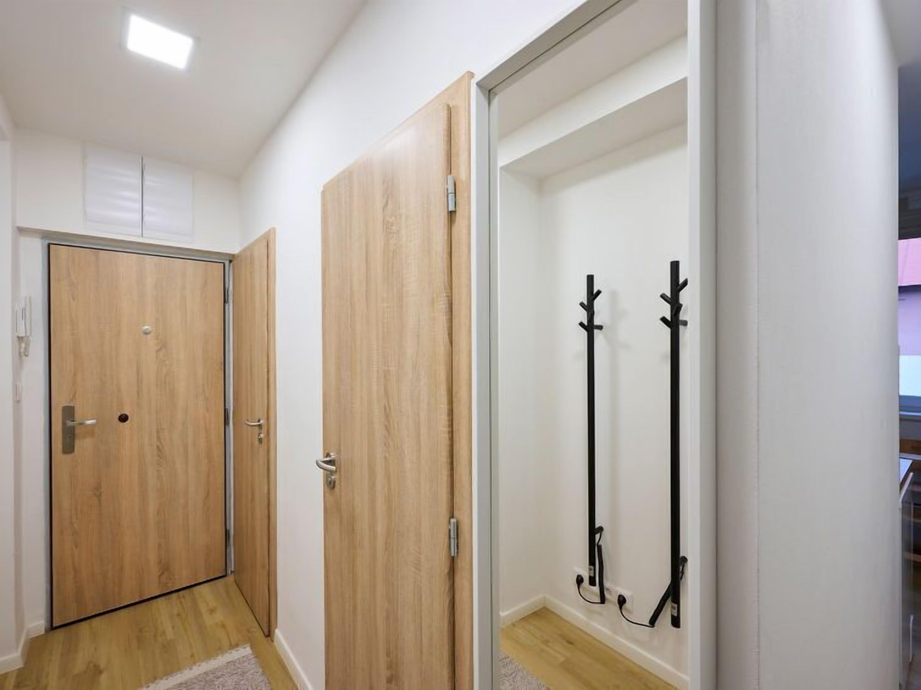 A hallway with wooden doors and a coat rack.