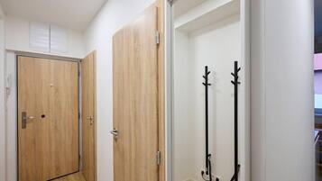 A hallway with wooden doors and a coat rack.
