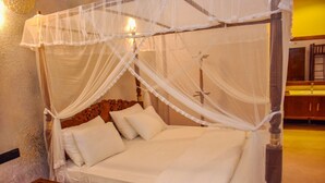 A four-poster bed with a canopy, wooden headboard, and white bedding.