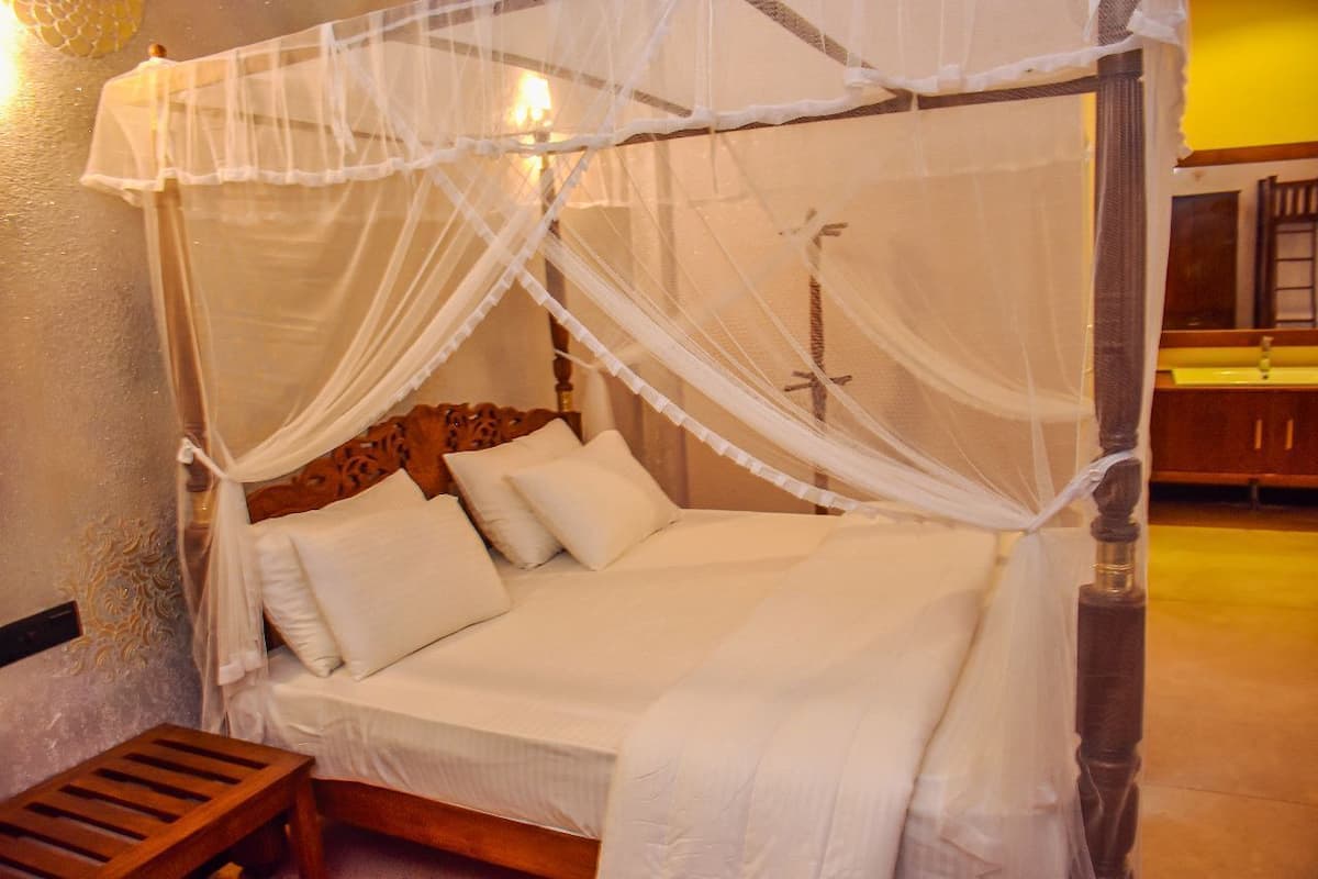 Un lit à baldaquin avec des poteaux aux quatre coins, une tête de lit en bois et du linge de lit blanc.
