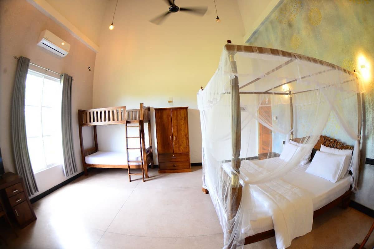 Une chambre à coucher avec un lit à baldaquin, un lit superposé, une armoire en bois et un ventilateur de plafond.