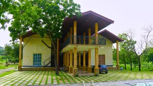 A two-story house with a balcony, a swimming pool, and a garden.