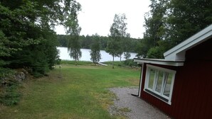 Ein rotes Gebäude mit einem Kiesweg, der zu einer Rasenfläche und einem See im Hintergrund führt.