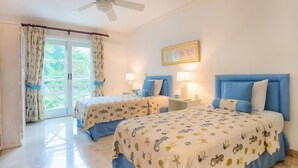 Une chambre avec deux lits, un ventilateur de plafond et une vue sur la verdure.
