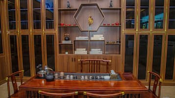 Una mesa de comedor de madera con sillas, rodeada de armarios de madera con estantes.