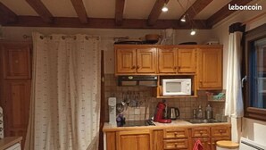 Eine Küche mit Holzausstattung, einer Mikrowelle, einer Kaffeemaschine und einer gefliesten Spritzschutzwand.
