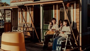 A wooden cabin with a porch, two chairs, and a large barrel. - ZEKKEI SEASIDE NAHAMA (Yokosuka)