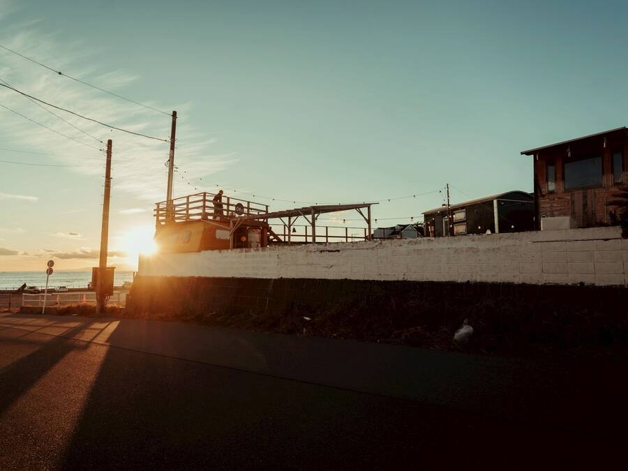 A coastal building with a brick wall, a wooden structure, and a view of the sea.