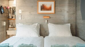 A double bed with white bedding and light blue towels, a wooden wall, a framed picture, and a bedside table with a lamp. - ZEKKEI SEASIDE NAHAMA (Yokosuka)