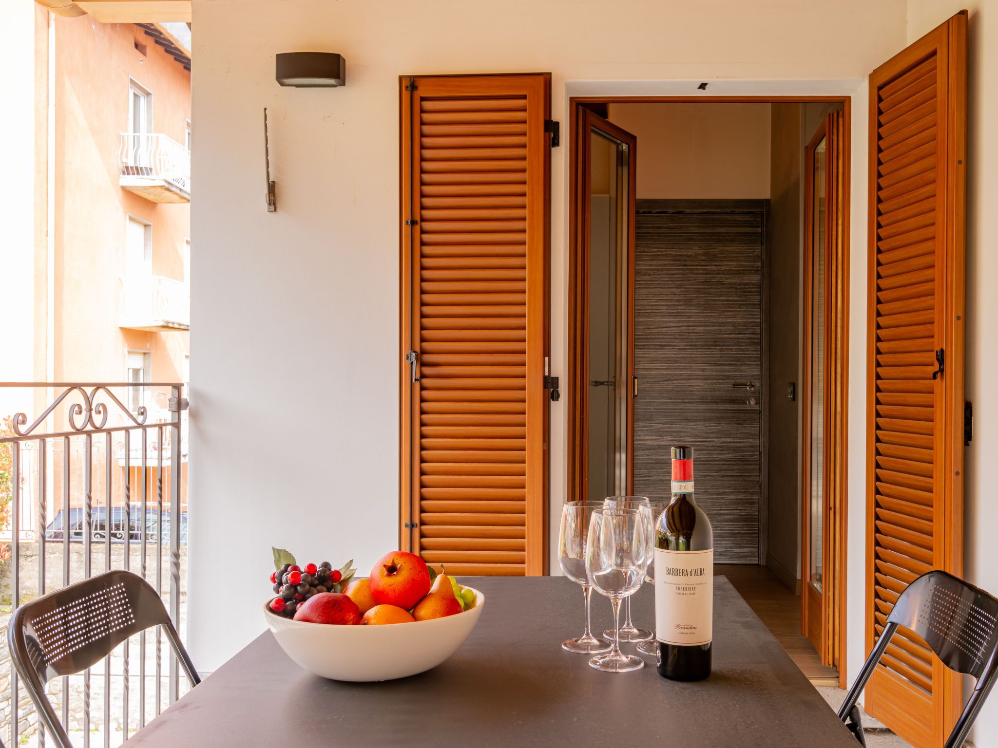 Une table à manger avec un saladier de fruits, des verres à vin et une bouteille de vin.