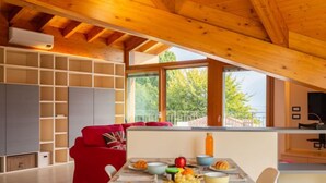 A cozy dining area with a wooden ceiling, a red sofa, and a table set with breakfast. - Apartment Salice by Interhome (Musso)