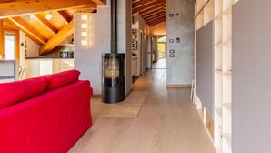 A modern interior with a high ceiling, a central fireplace, and a red sofa. - Apartment Salice by Interhome (Musso)