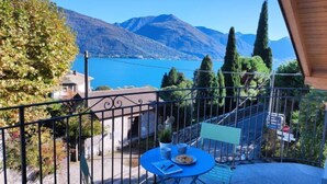 A balcony with a table and chairs, overlooking a lake and mountains. - Apartment Salice by Interhome (Musso)