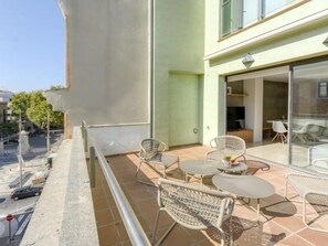 Ein Balkon mit Korbmöbeln, eine Glastür zu einem Innenraum und freie Sicht auf die Straße.