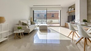 A modern living room with a sofa, a small round table, and a dining area with a white table and chairs. - Lizarran by Interhome (Figueres)