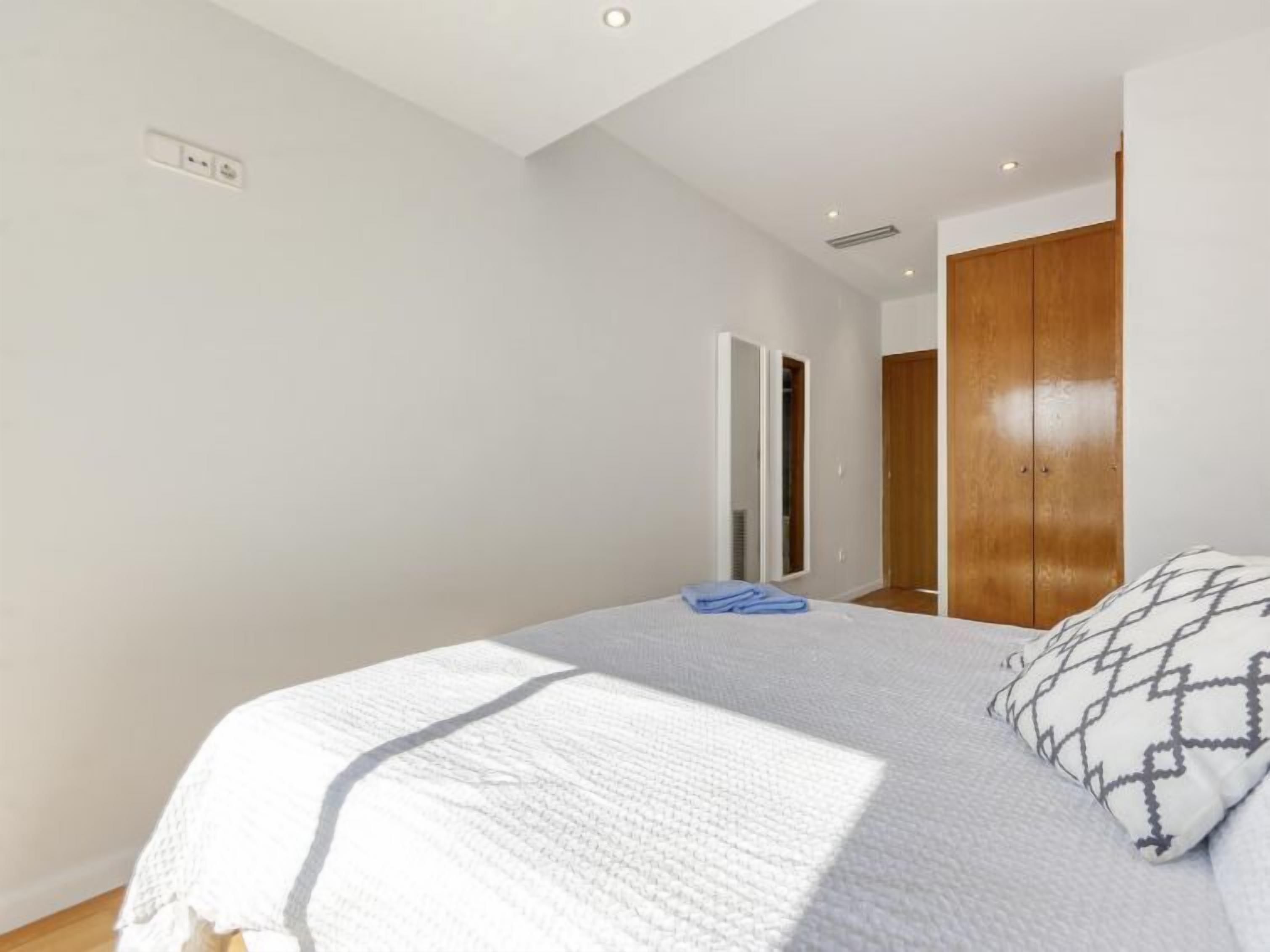 Quarto com cama, guarda-roupa e espelho.