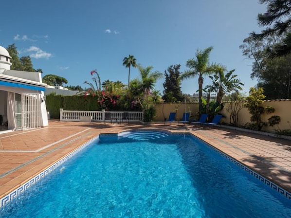 Relax by the pool surrounded by lush greenery and comfortable lounge chairs.