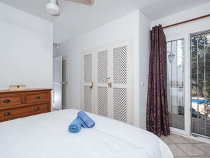 Enjoy a restful stay in this inviting room, featuring a comfortable bed, dresser, and sliding door to an outdoor area.