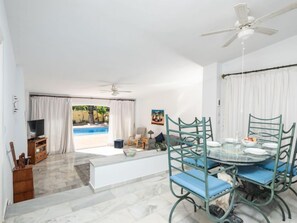 Relax in a spacious living area with a dining space, featuring a large window overlooking a serene pool view.