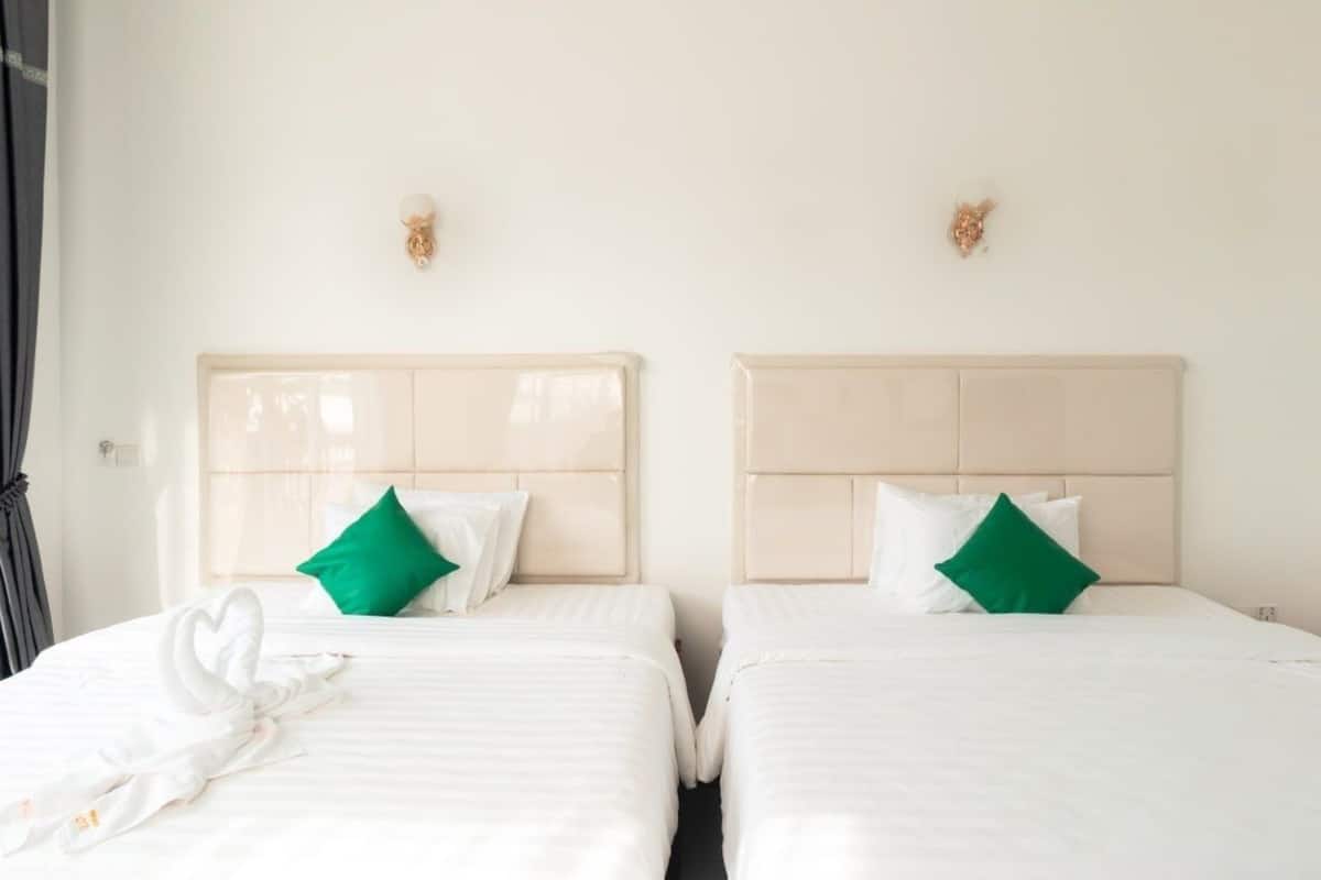 Two single beds with headboards, white bedding, and green pillows.