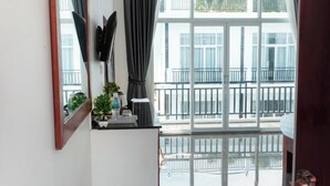 A hotel room with a large window, a small table with a plant, and a door with a handle. - Koh Dach View Boutique (Phnom Penh)