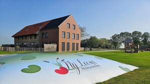 Un parque infantil con un letrero que dice 'Nij Leons Recreatiepark' y un edificio con techo inclinado.