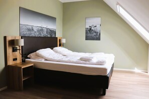 A neatly made bed with white linens, a wooden bedside table with a lamp, and two wall-mounted lamps. - Stylish Frisian Villa with Garden (Leons)
