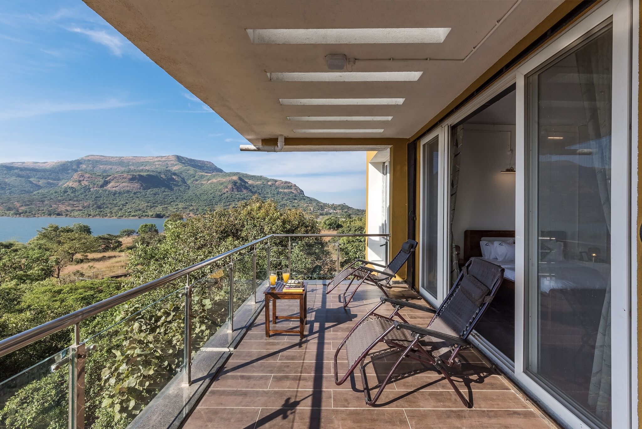 Un balcon avec une table, deux chaises et un lit.