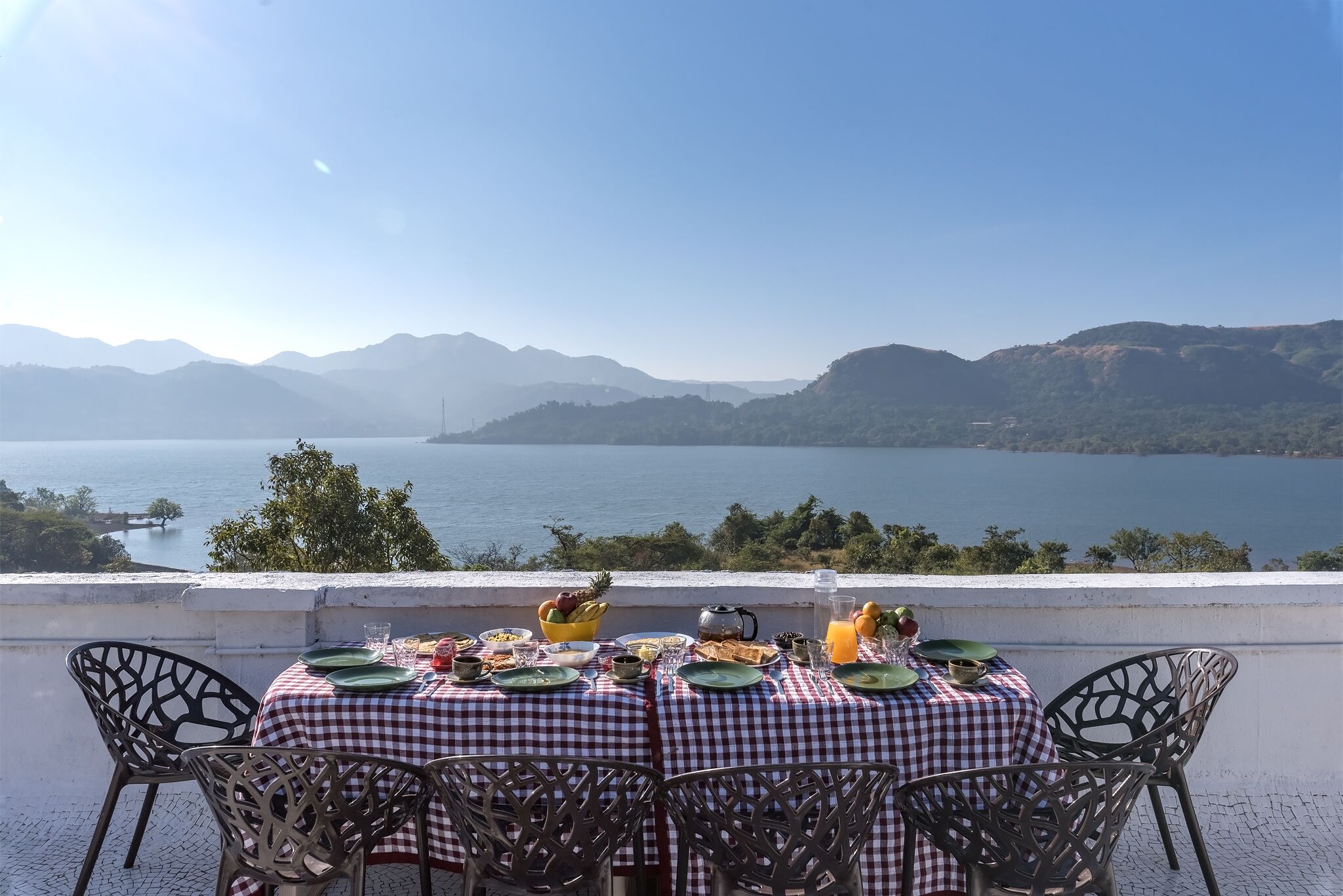 A table set for breakfast with a view of a lake and mountains.
