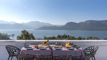 A table set for breakfast with a view of a lake and mountains.