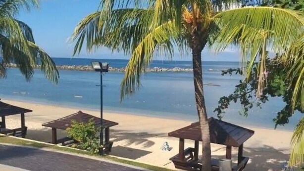 Une vue sur la plage, avec des palmiers et un kiosque.