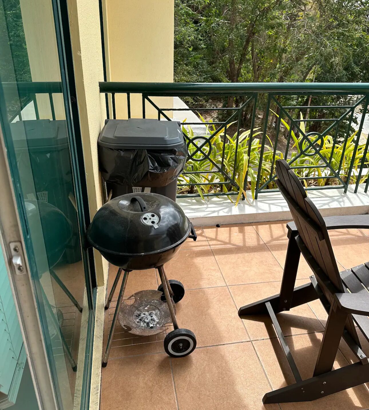 A patio with a grill, a chair, and a glass door.