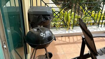 A patio with a grill, a chair, and a glass door.