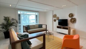 Un salon moderne avec un canapé, une table basse, un meuble pour la télévision et un fauteuil orange vif.