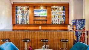 A bar area with a wooden ceiling, a large TV screen, shelves with bottles, and bar stools. - ENTEBBE TRAVELLER'S HOTEL (Entebbe)