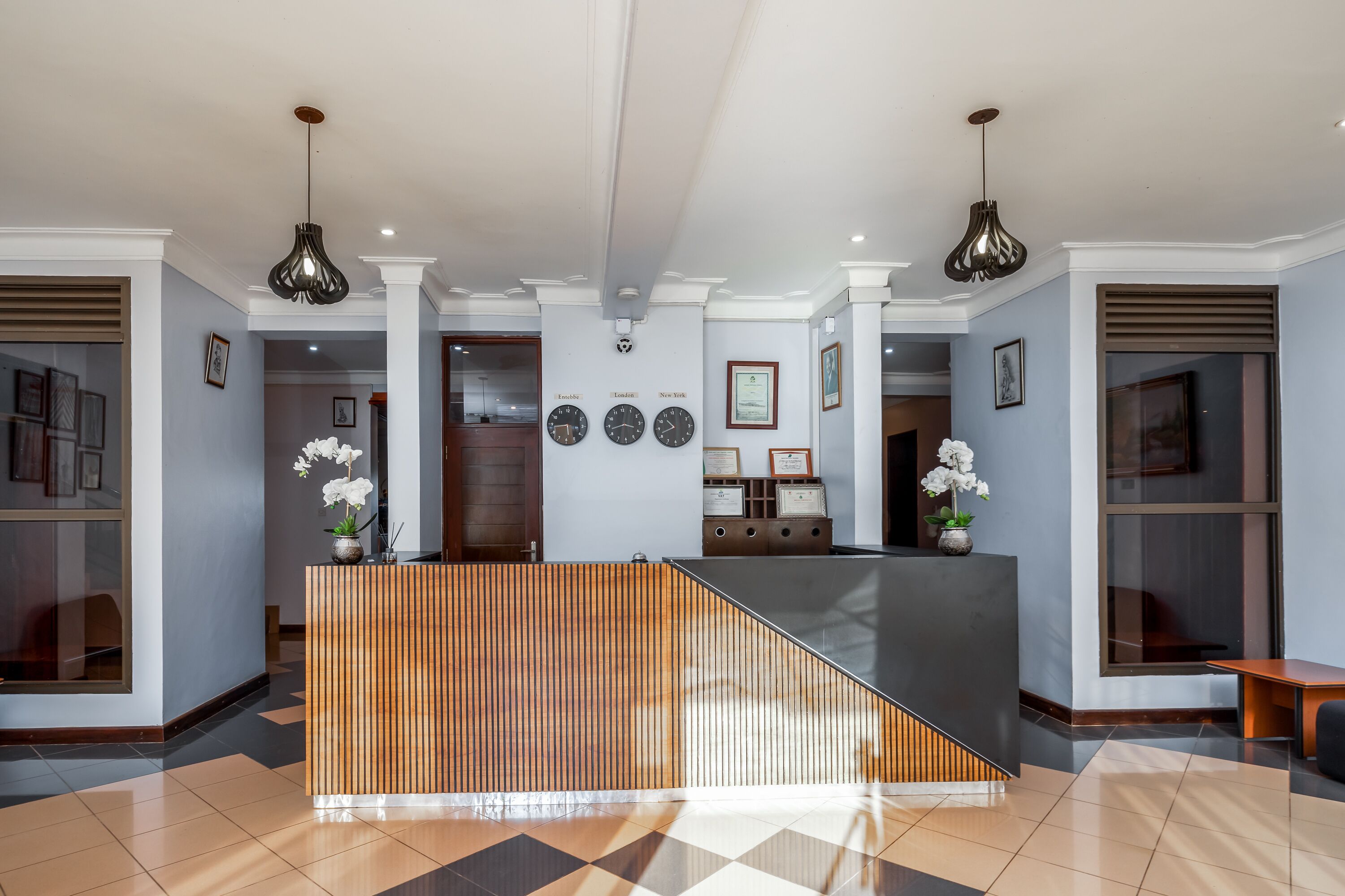 A reception area with a wooden reception desk, a black counter, and a tiled floor.