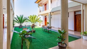A courtyard with artificial green turf, potted plants, and outdoor furniture. - ENTEBBE TRAVELLER'S HOTEL (Entebbe)