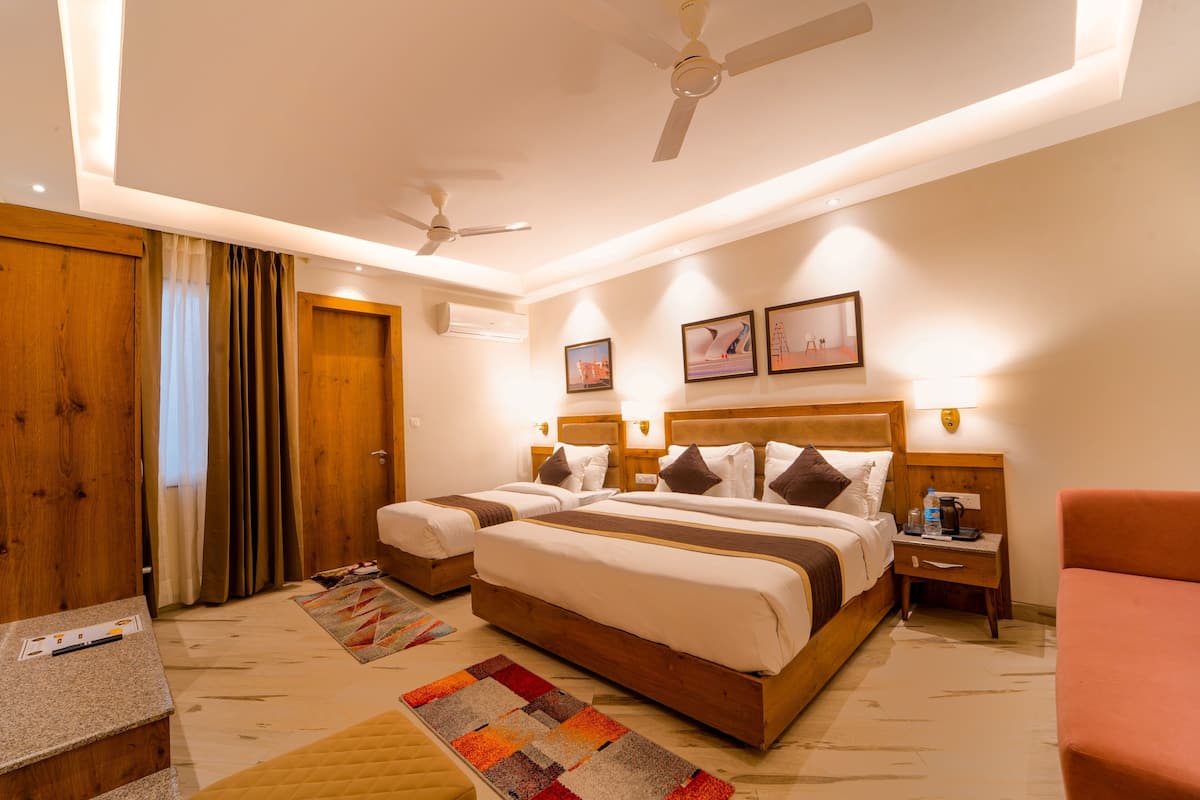 A hotel room with a large bed, two bedside tables, a desk, a chair, a ceiling fan, and two wall-mounted lamps.