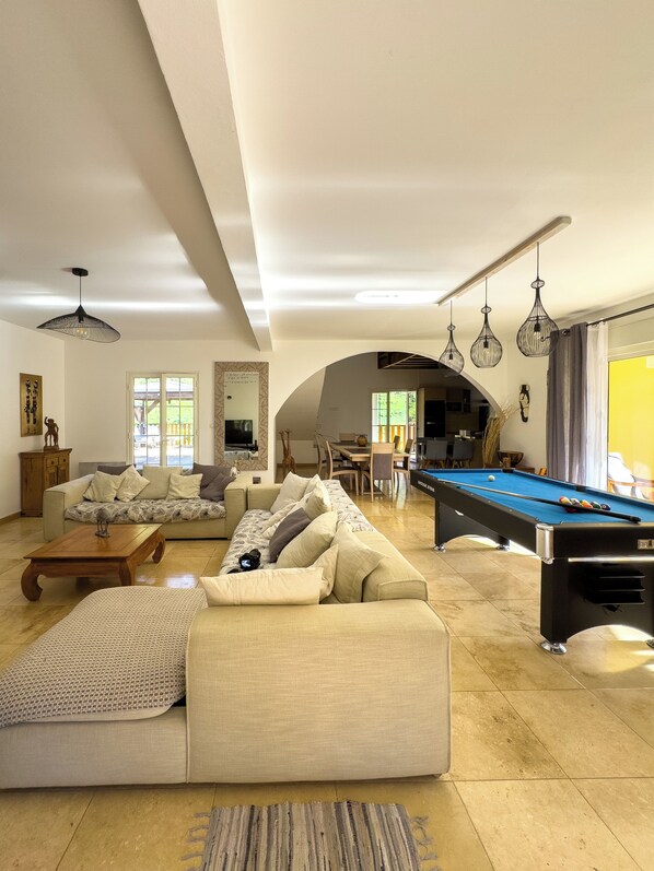 Un salon spacieux comprenant une table de billard, un ensemble de canapés et un coin repas.