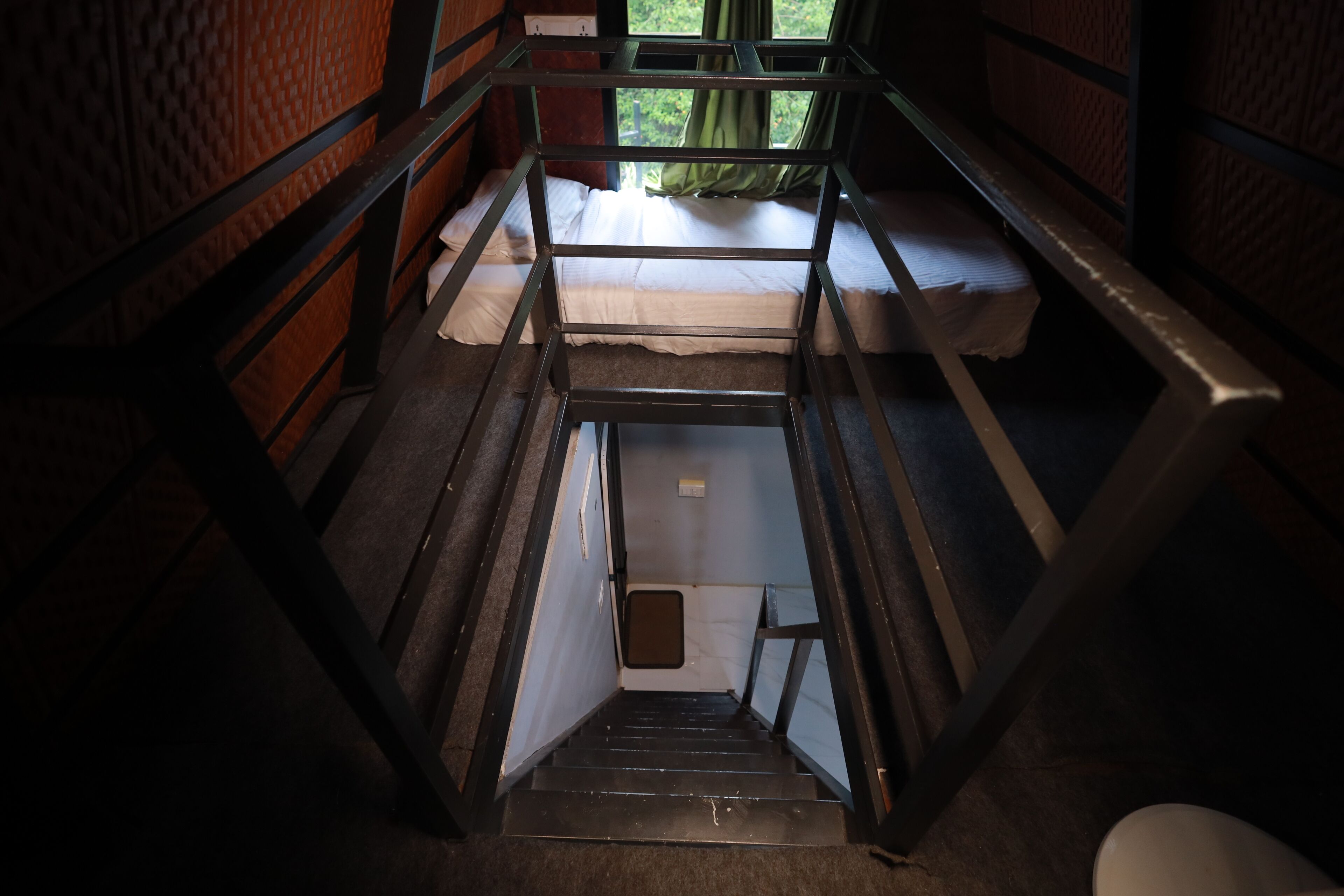 A bunk bed with a small window, a wooden door, and a carpeted floor.