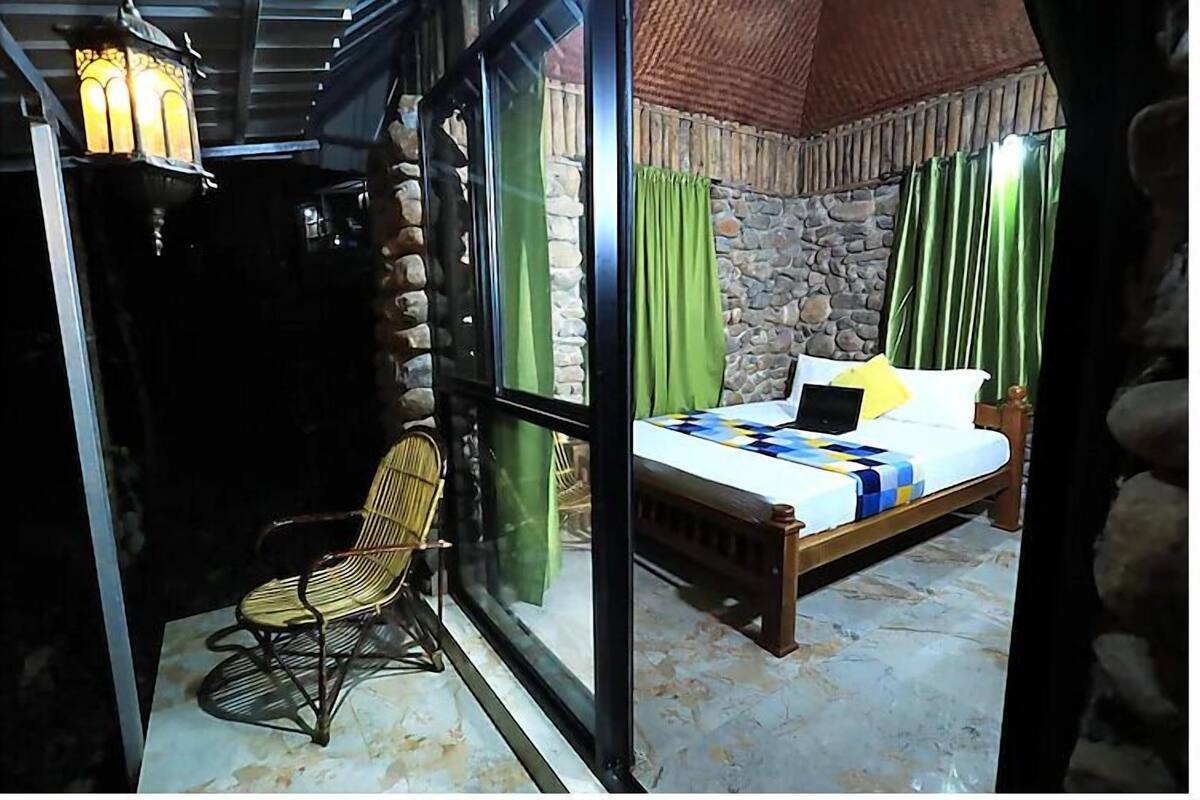Quarto com uma cama, uma cadeira e uma parede de pedra.