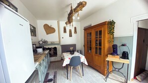 A compact kitchen with a dining area, wooden cabinets, a refrigerator, and a coffee machine. - Le Paradis des Bulles (Lisse-en-Champagne)