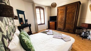 A bedroom with a large bed, a wardrobe, a television, and a window with curtains. - Le Paradis des Bulles (Lisse-en-Champagne)